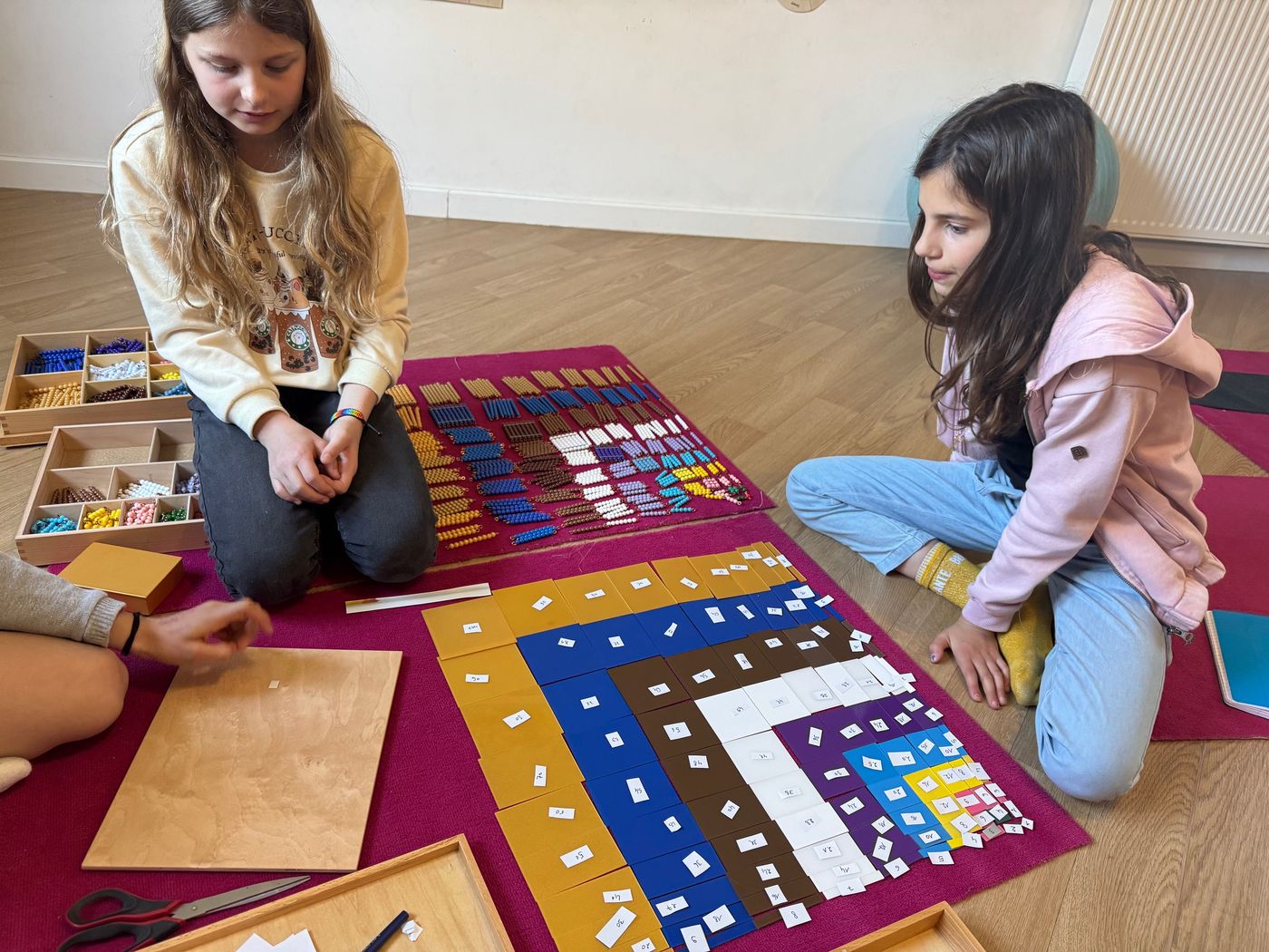 Deux élèves travaillant la multiplication sur le tapis du damier