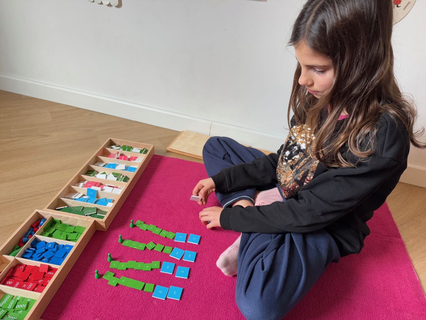 Enfant travaillant le matériel de numération Montessori sur un tapis